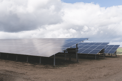 Kilka paneli słonecznych stoi na polu pod zachmurzonym niebem