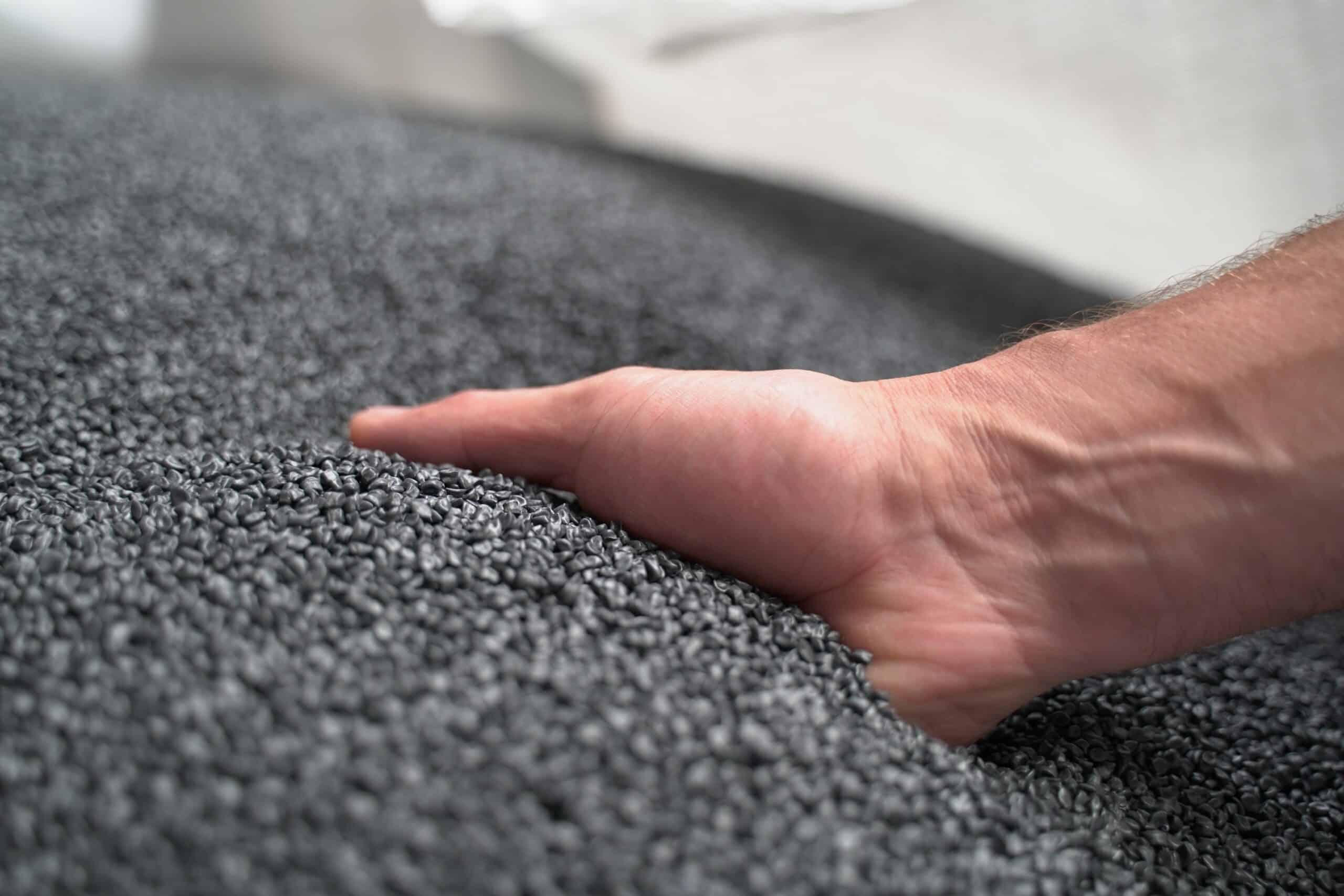 Ręka sięga do dużej ilości szarych granulek Ceramin®