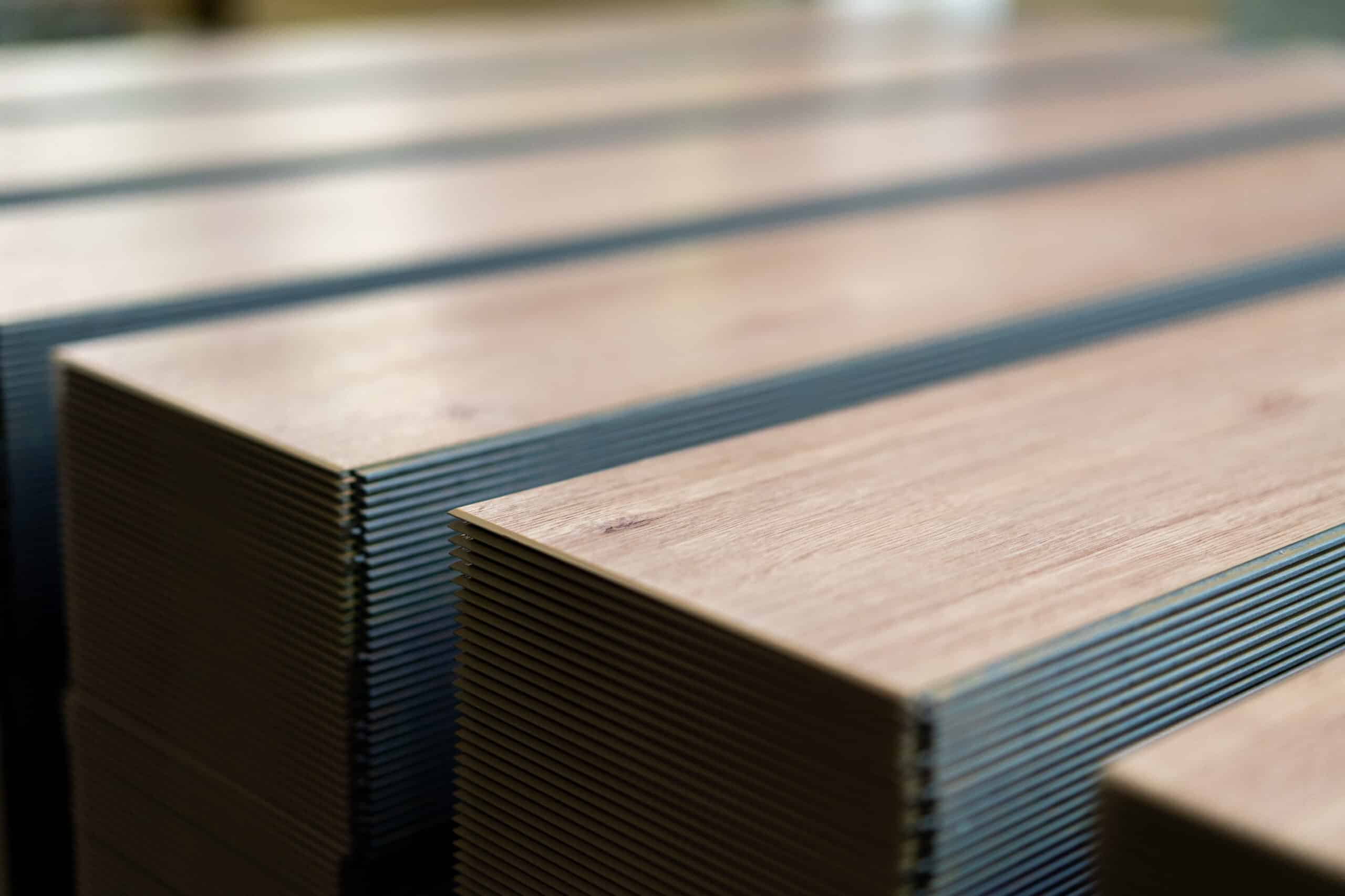 Kilka stosów desek leży obok siebie.