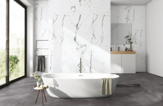Nowoczesna łazienka z wolnostojącą wanną, marmurową ścianą i jasną podłogą.