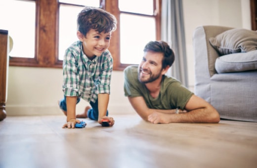 Ojciec i syn bawią się razem na drewnopodobnej podłodze