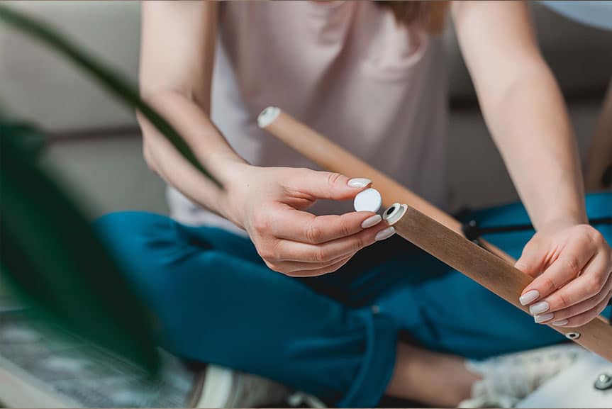 Kobieta mocuje filcowe ślizgacze pod krzesłem